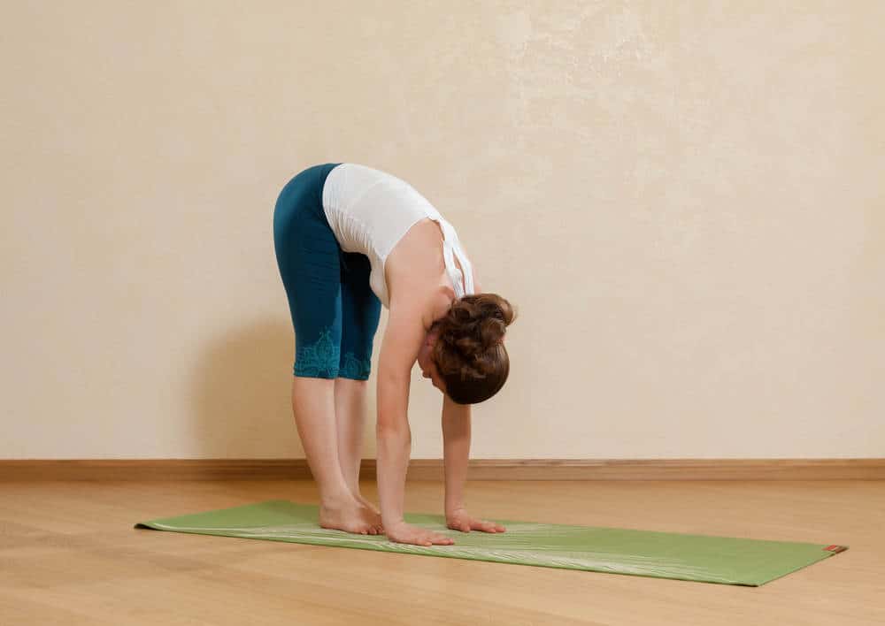 Caucasian woman is practicing yoga at studio (padahastasana).