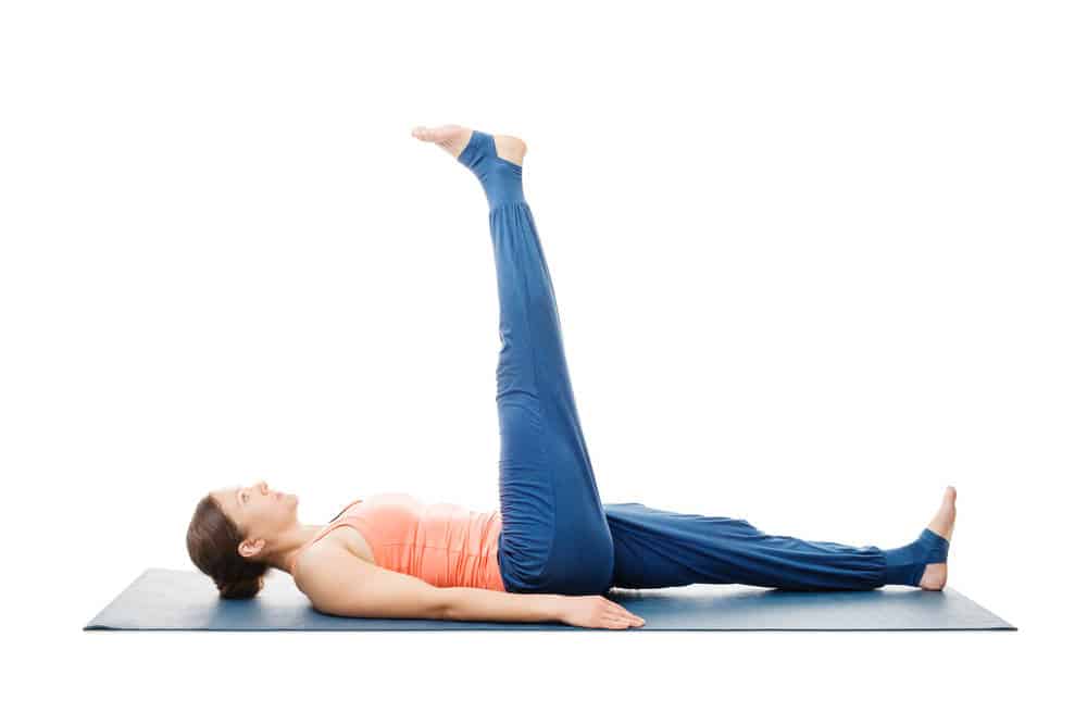 Woman doing yoga asana Uttanpadasana - lying down straight leg raise pose posture isolated on white background.